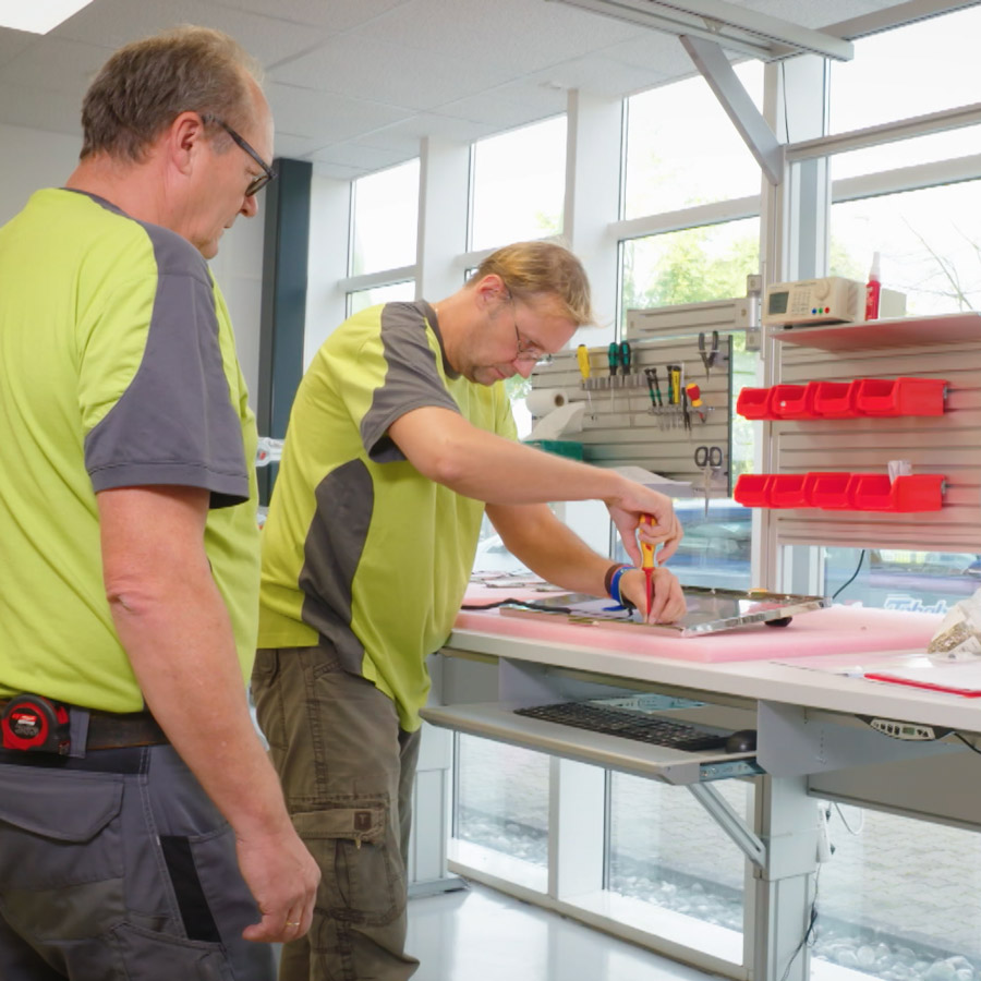 MintWeiterbilden_Qblue1 Zwei Menschen stehen in einer Werkstatt und arbeiten.