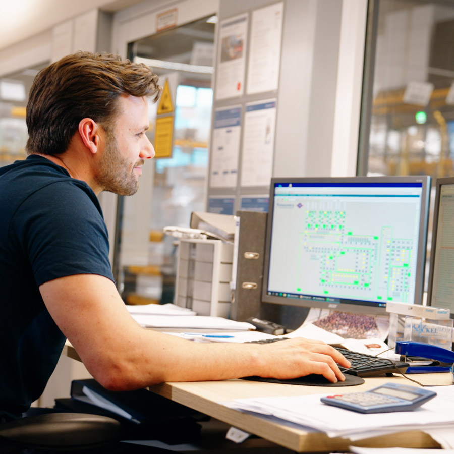 Qblue Ein Mann sitzt vor dem Computer und arbeitet